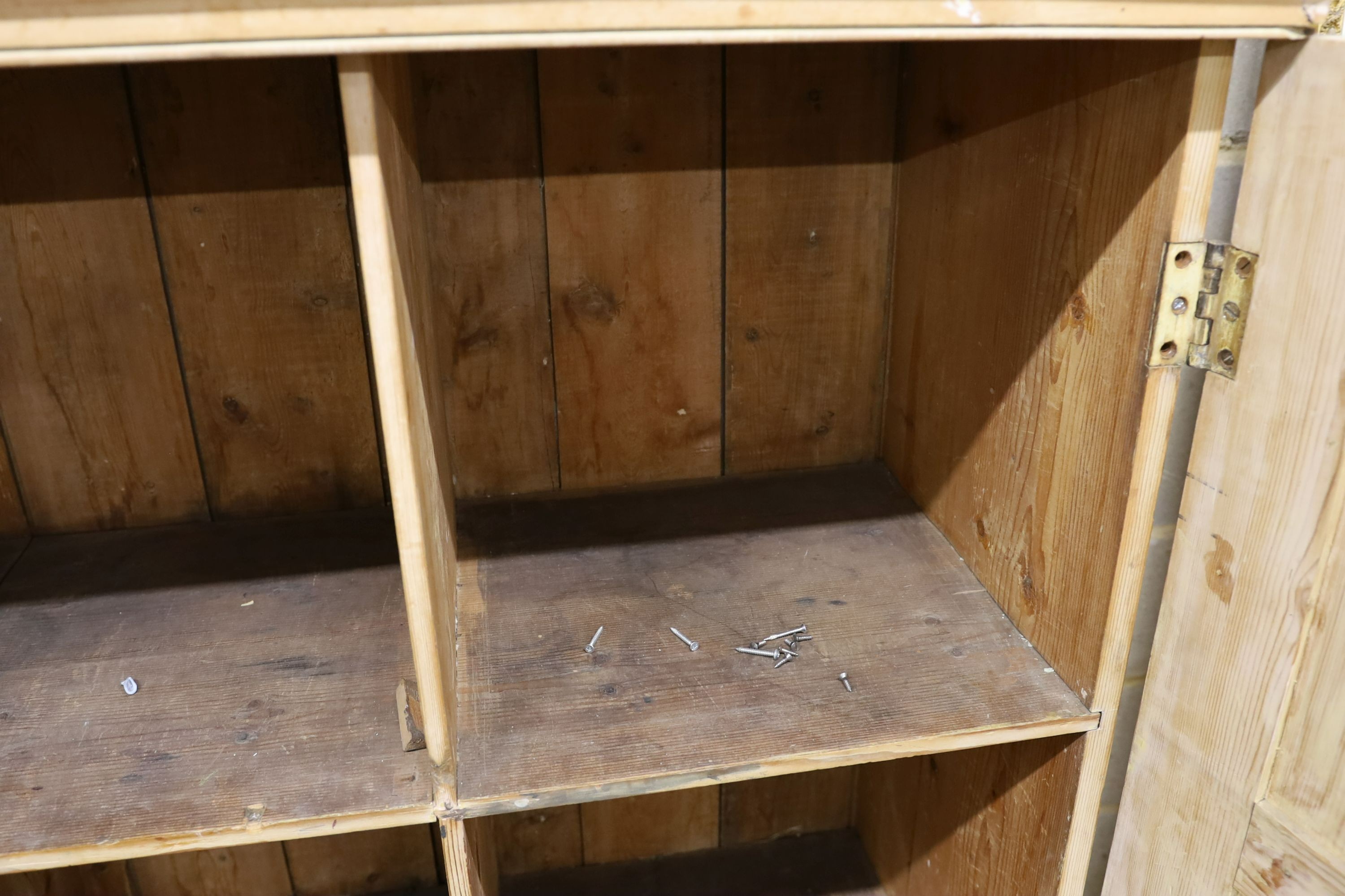A 19th century stripped pine hall cupboard modelled as a dolls house the two door nine window facade enclosing a compartmented interior, width 182cm, depth 46cm, height 192cm